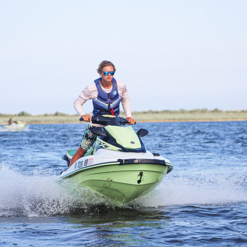 a man riding on the back of a boat in a body of water
